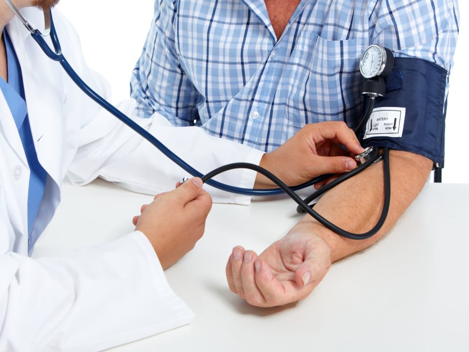 Older person taking a blood pressure test with a doctor.